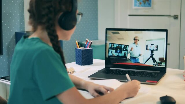 Online education concept. Schoolgirl participating in an online call using her laptop