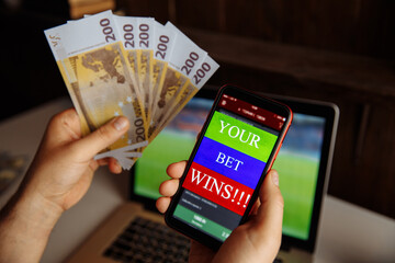 Lucky winner at football betting with euro money in hands near laptop.