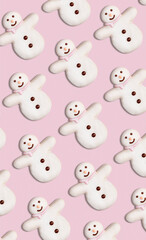 Vertical pattern of Christmas cookies in the shape of snowman decorated with icing sugar and fondant on a pink background