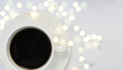 on a light background among bokeh white Cup on a saucer with black coffee