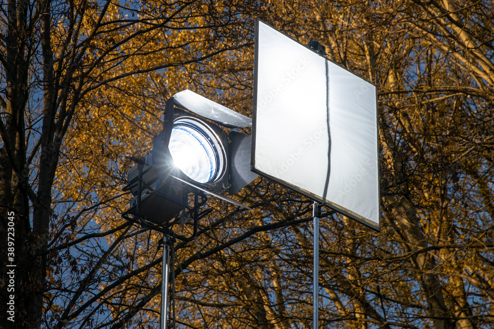 Poster lighting spotlight with diffuser in the park. lighting equipment for filming