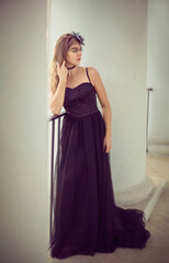 Fototapeta premium A girl in a long black dress walks through the old city