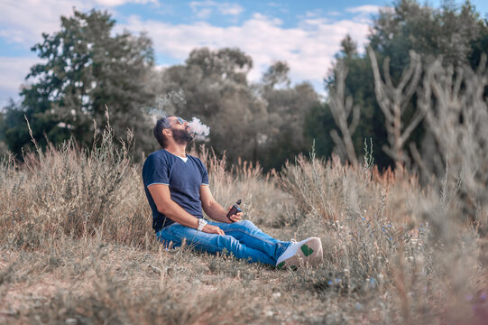 Stylish smoker in the fresh air smoking an electronic cigarette. Health concept.