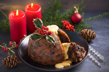 Fototapeta na wymiar Richly spiced Christmas pudding cake with custard and Christmas decorations