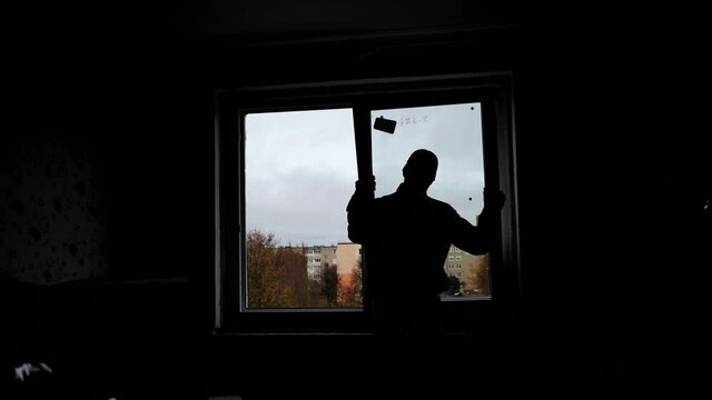 Silhouettes of builders install plastic windows in the house.