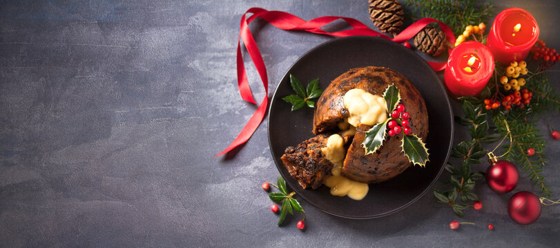 Richly spiced Christmas pudding cake with custard and Christmas decorations. Overhead, flat lay photo, copy space