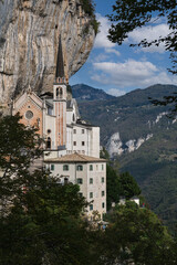 Fototapeta na wymiar View of the church on a steep cliff. Italian church at high altitude in the Alps. The sanctuary is high in the cliffs of Italy. The unique Sanctuary Madonna della Corona church in the rock.