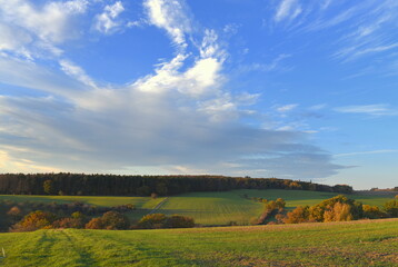 Wolkengebilde am blauen Himmel über Landschaft mit Feldern