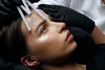 Beautician in gloves making measuring of eyebrows