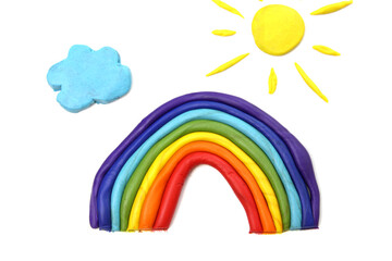 Obraz premium Plasticine rainbow near blue clouds on white background