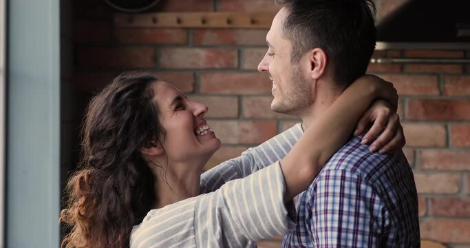 Side close up view happy wife put arms around husband neck, 35s couple in love move slow dance while looking at each other touch foreheads enjoy romantic date. Newlyweds, romance relationships concept