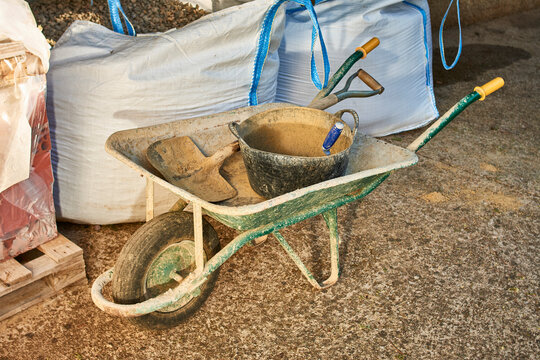 construction tools and building materials. wheelbarrow, spade, trowel, sacks of gravel and sand