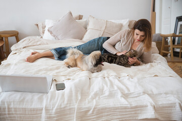 Woman lying on the bed with her pets little dog and cat
