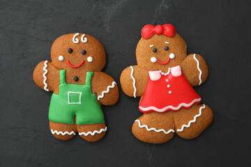 Gingerbread man and woman on black table, flat lay. Delicious Christmas cookies