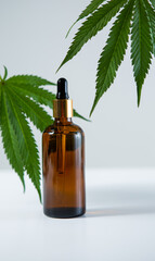 Glass jar with cannabis product and hemp leaves on gray background, close up