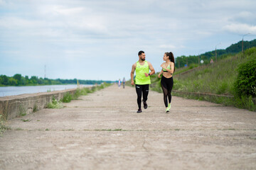 Fototapeta premium Running young couple in stylish sportswear outdoor in cloudy weather, healthy active lifestyle