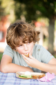 A beautiful boy eats a meal in the park