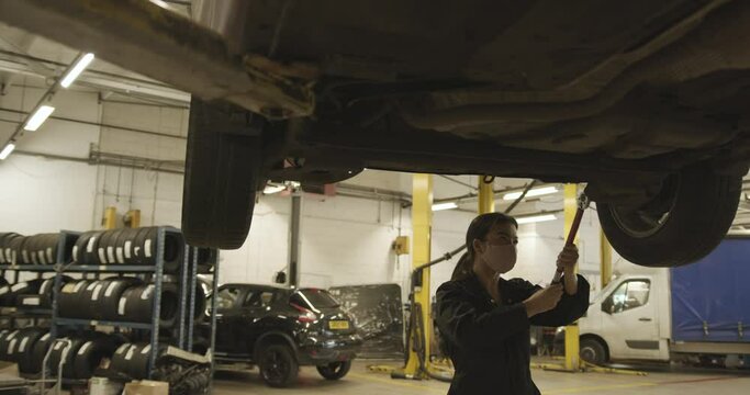 Female Car mechanic changing vehicle tire in automotive workshop
