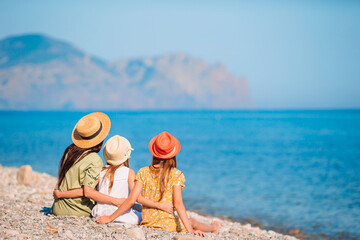 Adorable little girls and young mother on tropical white beach