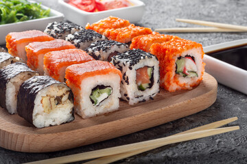 Sushi set on a wooden Board.Set of rolls with ginger, soy sauce and wooden sticks.