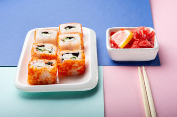 California and Philadelphia rolls on a white plate with ginger.