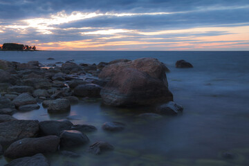 Fototapeta na wymiar Blue hour view of Baltic sea coast with erratic boulders covered with seaweed.