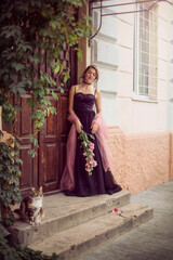 
girl in a black dress and a bouquet of flowers on the street of the old city