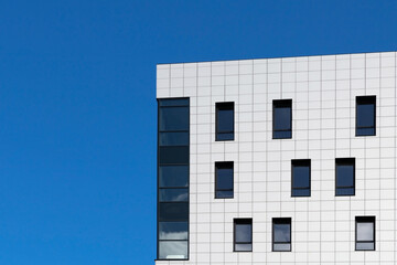 Urban abstract image. Part of the facade of a modern building with copy space on a blue sky background.