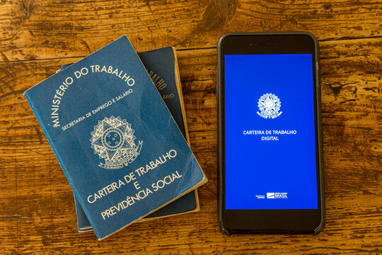Rio de Janeiro, Brazil - October 19, 2019: a digital working Brazilian working permit, the CTPS, with the traditional paper document on a wooden table