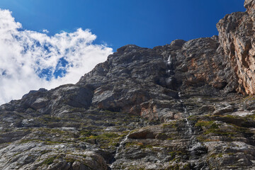 sheer rock with a waterfall against the sky