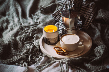 Cup of coffee on tray in cozy winter bad with wool blanket