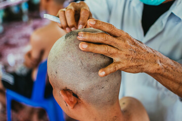Young man getting his hair shaved by old skilled man. Close up of Asian man shaving hair.
