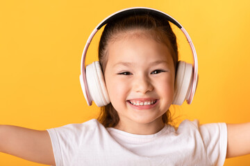 Smiling asian girl enjoying music using headset