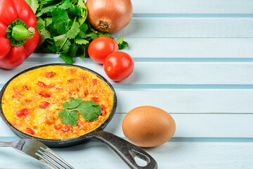 Omelet with onions and bell peppers on a blue background. National cuisine. Copy space.