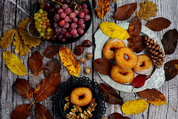 Sweet food, junk food and food concept - close up of fried donuts, grapes and walnuts on a wooden table. Top view