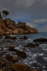 Seascape of a rocky coast that juts out into the Mediterranean Sea, at sunset, with a cloudy sky