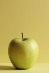 Single green apple on a yellow horizontal background. Minimalism concept.