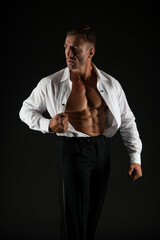 Muscular man show fit torso with six pack abs in open shirt formal style black background, six-pack