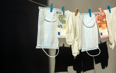 latex gloves and a medical face mask hang, euro banknotes money on clothespins hard light gray background . spending safety concept during covid-19 coronavirus pandemic.