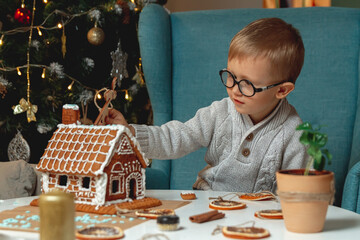 Little boy decorates christmas gingerbread house