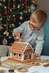 Little boy decorates christmas gingerbread house