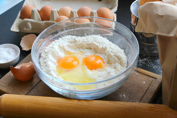 A bowl of flour and egg on the kitchen table.Preparation of home-made dough. Baking ingredients