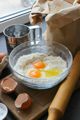 A bowl of flour and egg on the kitchen table.Preparation of home-made dough. Baking ingredients