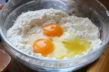 A bowl of flour and egg on the kitchen table.Preparation of home-made dough. Baking ingredients