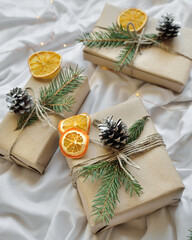 Cosy home flat lay composition with present boxes, blank copybook, a pen, tea and cones on a bed. Holiday shopping list, wish list or New Year Goals concept, presents checklist. Selective focus