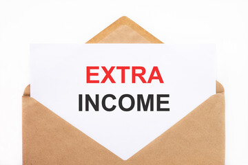 A white sheet with the text extra income lies in an open craft envelope on a white background with copy space. Business concept image