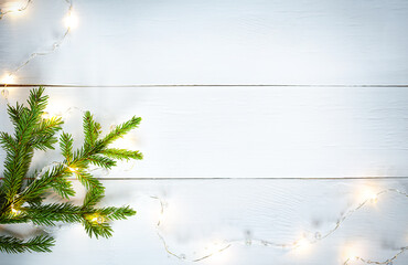 Christmas decoration green fir branches and yellow garland on white wooden board
