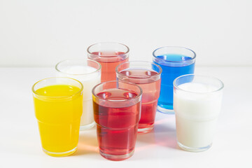 Glasses of lemonade in different colors against a white background