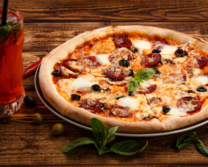 Pizza with meat and olives on a wooden background