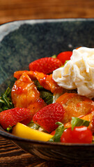 salad with chicken and strawberry wedges on a wooden background